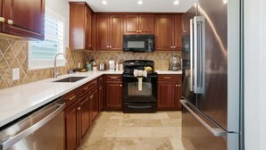 Una cocina con gabinetes de madera, un refrigerador de acero inoxidable, un microondas y una estufa.