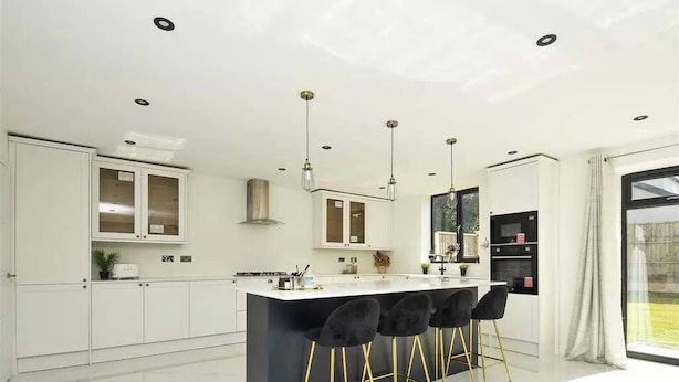 A modern kitchen with white cabinets, a central island with bar stools, pendant lighting, and a large window. - Cozy Urban Retreat in Wolverhampton (Wolverhampton)