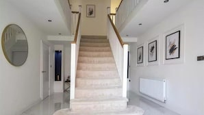 A staircase with a wooden handrail, white walls, and framed artwork on the upper landing. - Cozy Urban Retreat in Wolverhampton (Wolverhampton)
