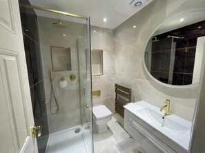 Un bagno moderno con doccia vetrata, un water e un mobile lavabo.