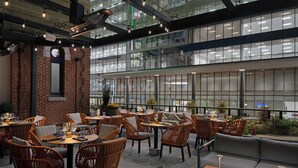 Un'area pranzo moderna e interna, con mobili in vimini, una parete decorata con mattoni e ampie finestre.