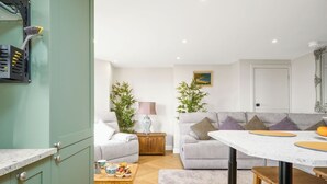 Una sala de estar moderna con un sofá, una mesa de comedor y una zona de cocina con armarios y una encimera.
