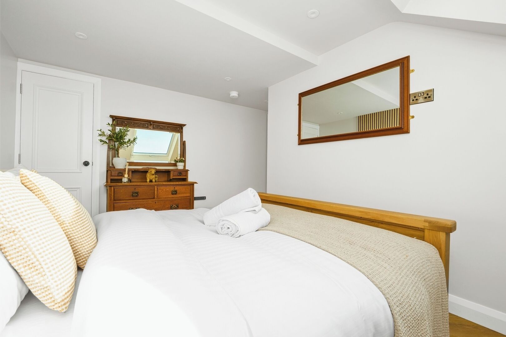 A bedroom with a bed, a dresser, a mirror, and a door.