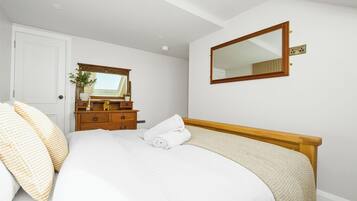 A bedroom with a bed, a dresser, a mirror, and a door.