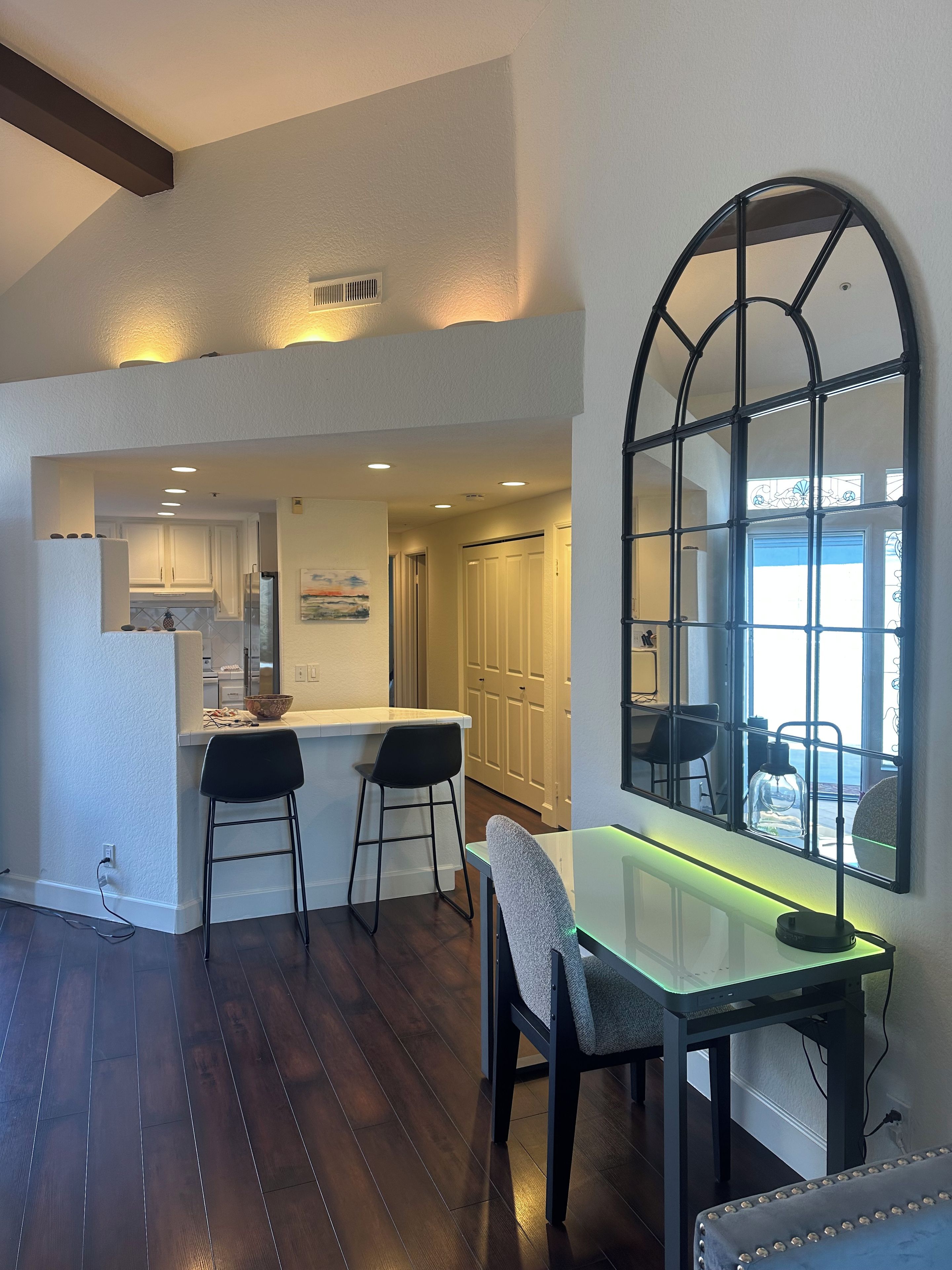 A modern kitchen with a bar area, wooden flooring, and a dining table with chairs.