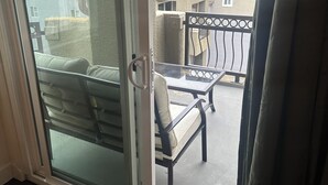 Una stanza con una porta scorrevole in vetro che si apre su un patio esterno con tavolo e sedie.