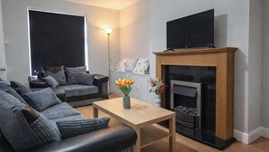A modern living room with a sofa set, a wooden coffee table, a fireplace, and a flat-screen TV. - 2 Bed Home - Parking, Wifi, Smart Tv (Nottingham)