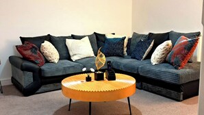 A sectional sofa with various patterned cushions, a round wooden coffee table, and a wall-mounted artwork. - 2 Bed Home - Parking, Private Garden, Wifi (Derby)