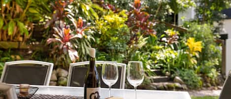 A table set outdoors with a bottle, glasses, strawberries, crackers, and cheese.