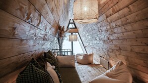 A cozy wooden interior with a sofa, pillows, and hanging lamps. - Family mountain retreat with jacuzzi, sauna, playground, and stunning forest views. (Sunger)