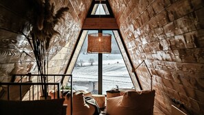 An attic room with a sloped ceiling, a hanging lamp, and a view of a snowy landscape through a large window. - Family mountain retreat with jacuzzi, sauna, playground, and stunning forest views. (Sunger)