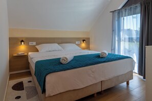A neatly made bed with a teal blanket, two bedside lamps, and a window with curtains. - Modern villa with pool near Ivanščica and Varaždin (Margečan)