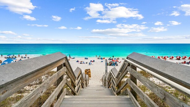 A wooden staircase leading to a beach with clear blue water and a sunny sky. - Salt and Sway (Miramar)