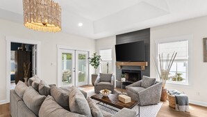 A modern living room with a large gray sectional sofa, a coffee table, a fireplace, and a flat-screen TV mounted on the wall. - Salt and Sway (Miramar)