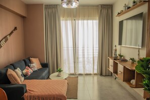 Un salon avec un canapé, une table basse, un téléviseur et une plante.