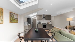 A modern kitchen with a skylight, a dining area with a table and chairs, and a green sofa. - The Luxury Secret Garden Retreat 3 bed 2 Bath (London)