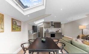 A modern kitchen with a skylight, a dining area with a table and chairs, and a green sofa. - The Luxury Secret Garden Retreat 3 bed 2 Bath (London)