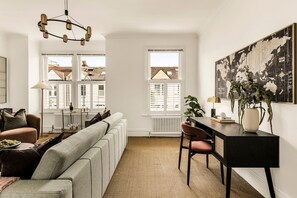 A modern living room with a sofa, a dining table, and a large world map on the wall. - The Luxury Chic Duplex Apartment 2 Bed 2 Bath (London)