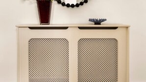 A white console table with perforated panels, a vase with flowers, and a round mirror with a black frame. - The Luxury Chic Duplex Apartment 2 Bed 2 Bath (London)