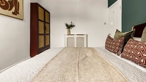 A bedroom with a patterned bedspread, a bedside table with a vase of flowers, and a large wardrobe. - The Luxury Chic Duplex Apartment 2 Bed 2 Bath (London)