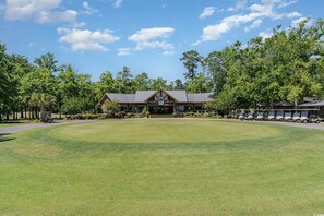 Ein Golfplatz mit Clubhaus, umgeben von Bäumen und Golfwagen.