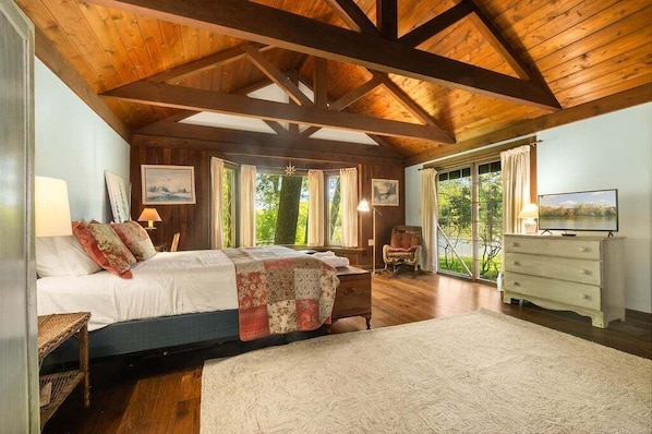 A bedroom with a bed, a dresser, a chair, and a television.