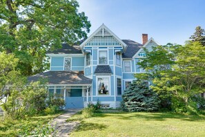 A large, two-story house with a prominent front porch, a chimney, and a well-maintained garden.