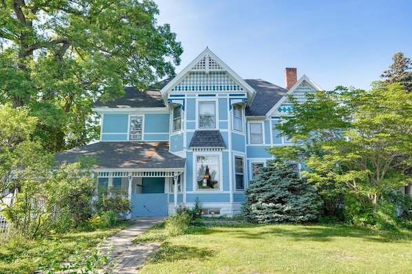 A large, two-story house with a prominent front porch, a chimney, and a well-maintained garden.