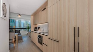 Een moderne keuken met houten kastjes, een inbouwoven en een raam met uitzicht op een stadsgezicht.
