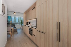 A modern kitchen with wooden cabinets, a built-in oven, and a window overlooking a cityscape. - Cloud 28 | 2BR Sky Residence | Downtown Miami (Miami)