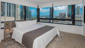 Een moderne hotelkamer met een groot bed, een nachtkastje, uitzicht op de stad door grote ramen en een stadszicht in een spiegel.