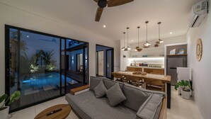 A modern living space with a pool, a dining area, and a kitchen. - Villa Irena (Canggu)