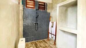 Un bagno con il water, una zona doccia con parete rivestita in piastrelle e pavimento in legno.