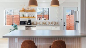 Une cuisine moderne dotée d’un éclairage suspendu, d’un four à micro-ondes encastré et offrant une vue sur l’extérieur.