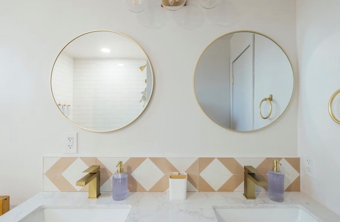 Une salle de bain avec deux lavabos, des robinets dorés et un miroir avec un cadre doré.