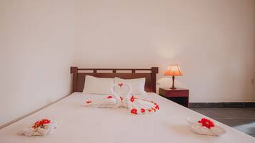 A hotel room with a neatly made bed, a bedside lamp, and a wall socket.
