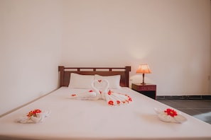A hotel room with a neatly made bed, a bedside lamp, and a wall socket. - Terrace Resort (Phu Quoc)