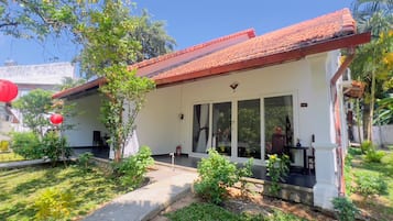 A building with a tiled roof, large windows, and a garden area with plants and a pathway.