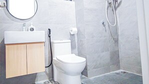 A bathroom with a toilet, sink, mirror, and shower. - Mall Suite at Sunsuria Forum by HCK (Shah Alam)