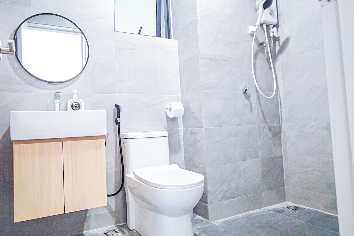 Une salle de bain équipée de toilettes, d’un lavabo, d’un miroir et d’une douche.