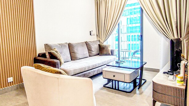 A modern living room with a sofa, a glass coffee table, and a desk with a chair. - Mall Suite at Sunsuria Forum by HCK (Shah Alam)