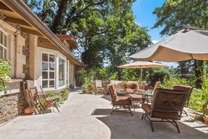 Eine Terrasse im Freien mit Steinböden, einem Tisch und Stühlen sowie einem großen Sonnenschirm.