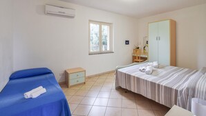 Un dormitorio con una cama, una mesita de noche, una ventana, un equipo de aire acondicionado y un armario.