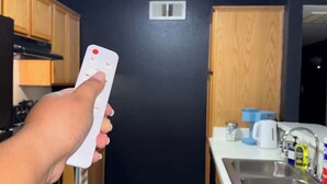 Una cocina con gabinetes de madera, una encimera blanca, un lavamanos de acero inoxidable y una lámpara en el techo.
