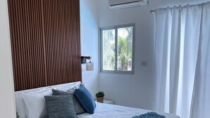 A modern bedroom with a bed, a window, an air conditioning unit, and a ceiling fan. - Surf View Penthouse @ Encuentro (Cabarete)