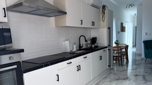 A modern kitchen with white cabinets, a black countertop, and a marble floor. - Surf View Penthouse @ Encuentro (Cabarete)