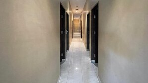 A long, narrow hallway with doors on both sides, leading to rooms.