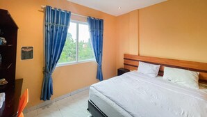 A bedroom with a bed, curtains, a nightstand, and a wall-mounted shelf.