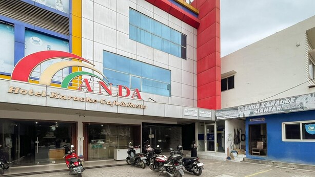 A building with a prominent 'ANDA' sign, indicating a hotel with karaoke and restaurant services.