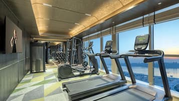 Un gimnasio con cintas de correr, elípticas y equipo de pesas.